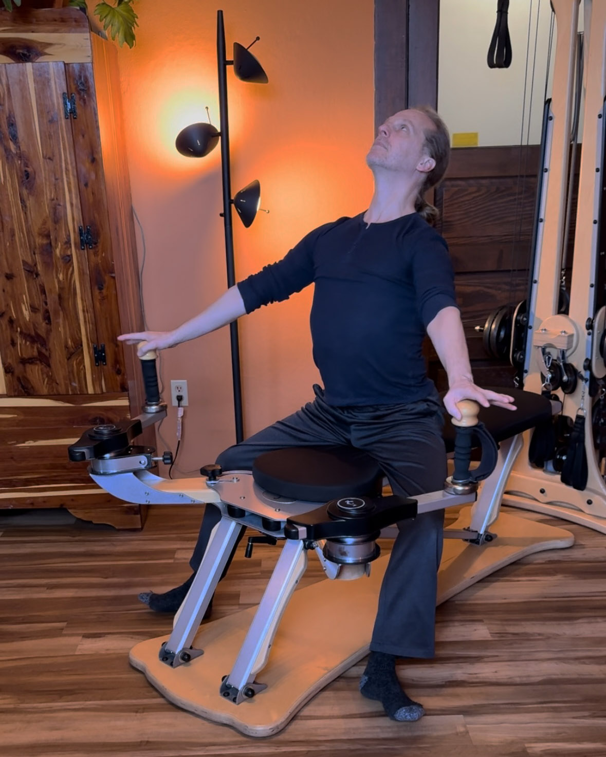 Gyrotonic® trainer Joseph Gillam performing balanced arch and curl exercise on pulley tower