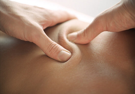 Two thumbs doing circular massage on client's back