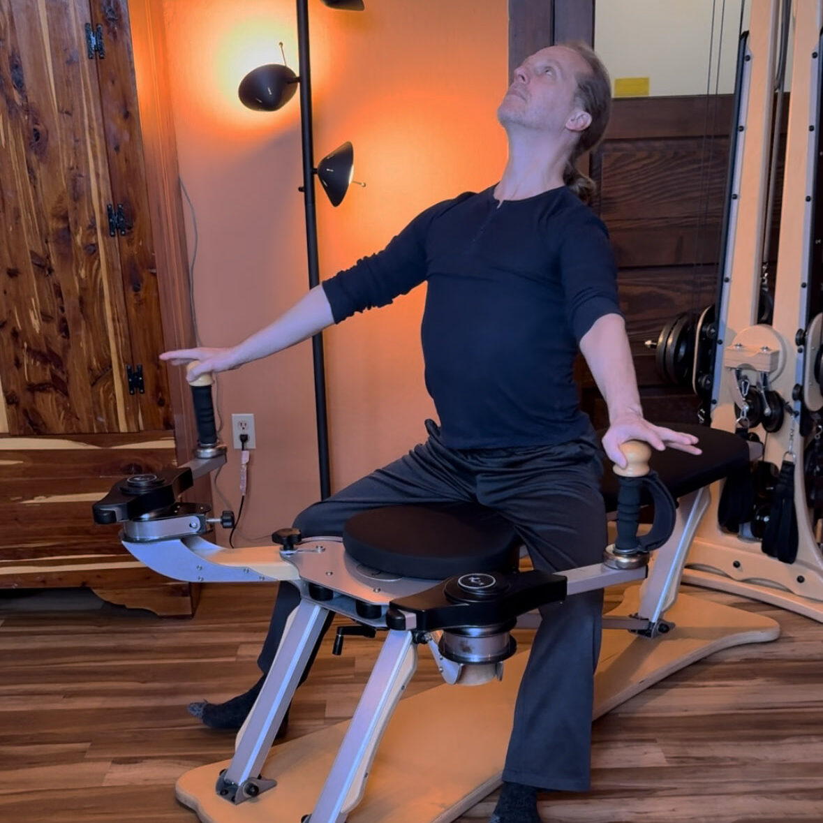 Gyrotonic® trainer Joseph Gillam performing balanced arch and curl exercise on pulley tower